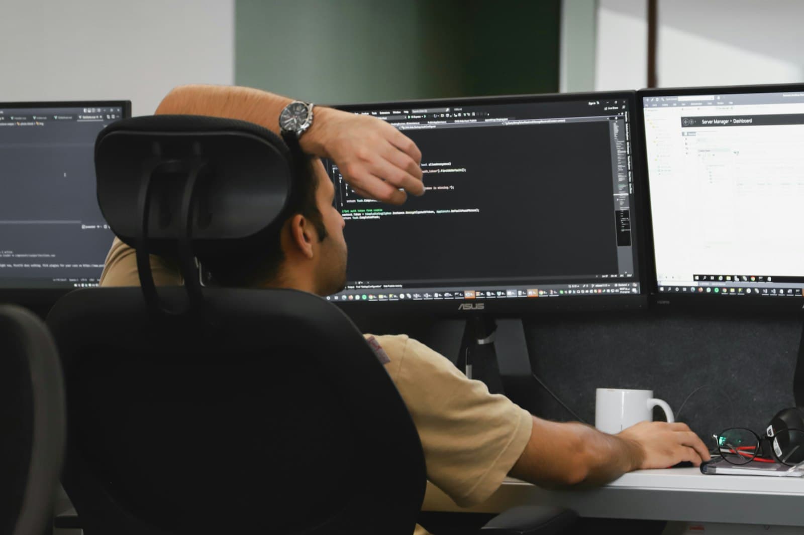 A developer at a desk in front of two monitors of code.