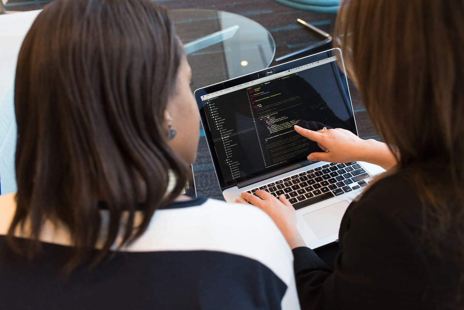 Two people working together at one laptop.