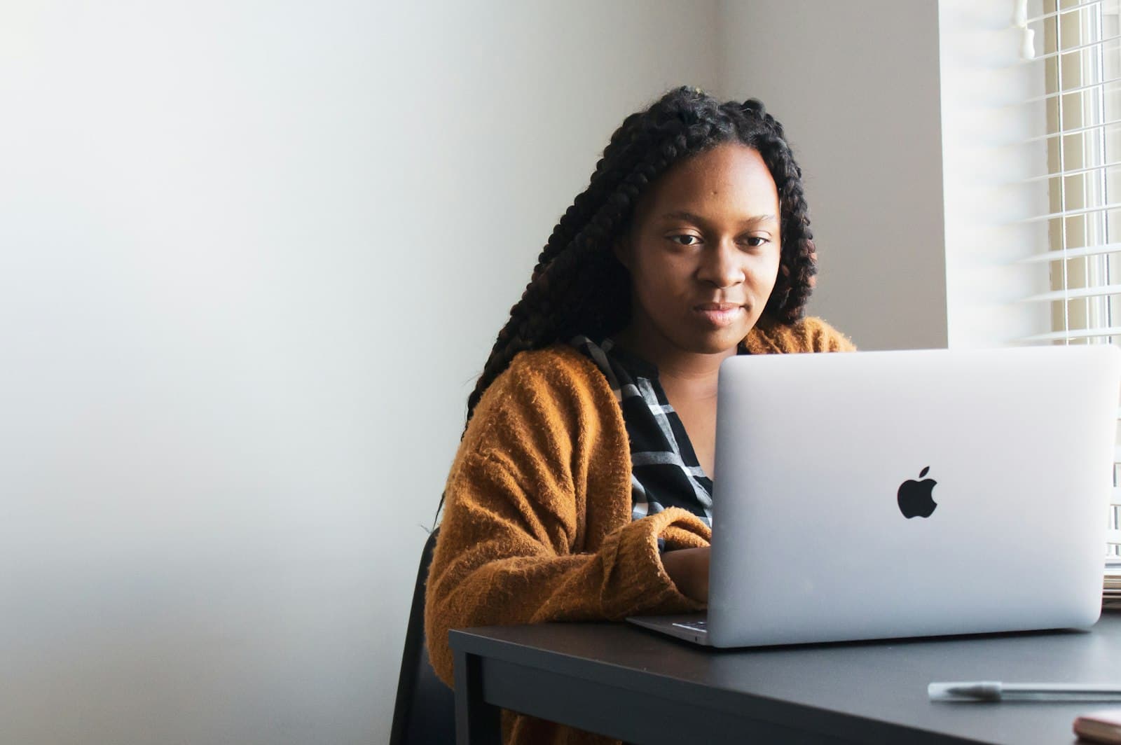 A woman working at a laptop at a desk in a shared workspace.